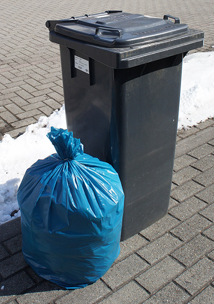 Foto: Ein blauer ABIKW Restabfallsack steht neben einem Restabfallbehälter zu Mitnahme bereit